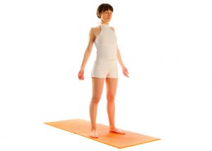 woman standing upright on yoga mat performing mountain pose