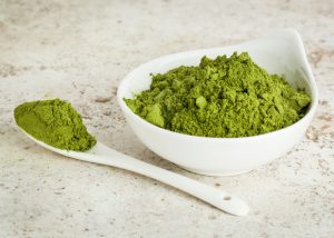 superfood moringa powder in a bowl and a spoonful beside it