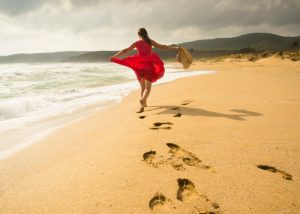 happy woman in red dress walking on a beach