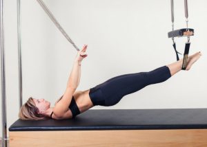 a woman using the pilates cadillac machine