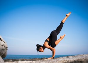 a woman performing a complex yoga pose on rocks