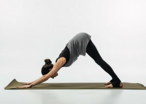 a woman doing the downward facing dog pose on a yoga mat