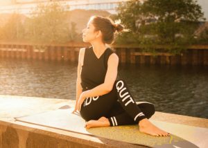 a woman performing a yoga pose by a river with the sun in her face