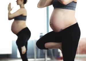 a pregnant woman doing yoga poses next to a mirror