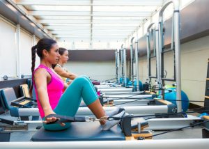 a woman using the pilates reformer machine in a gym