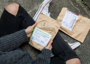 a girl holding onto packets of edible insect powders