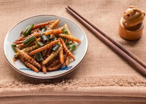 a small plate of fried mealworms with chopsticks on a table