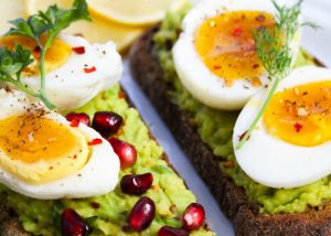 hard boiled eggs on avocado toast with pomegranate seeds