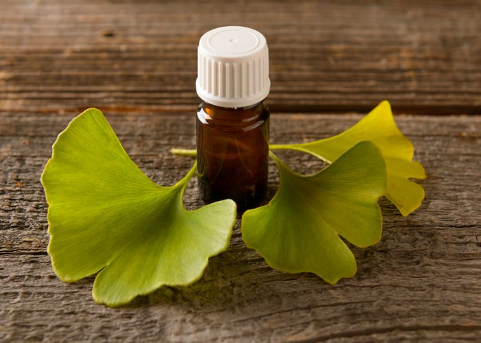 ginkgo biloba leaves and a bottle of extract on a wooden table