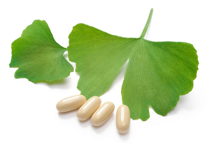 ginkgo biloba supplement pills and leaves on a white surface