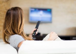 a woman holding a tv remote control on the couch