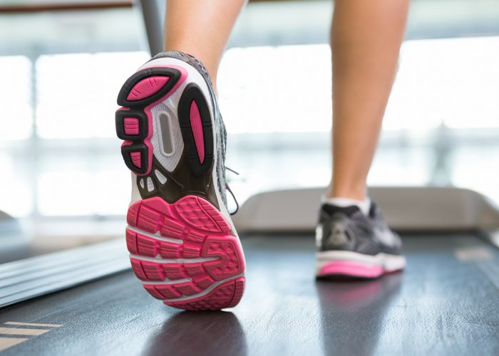 the sole of a woman's running shoes on a treadmill in the gym