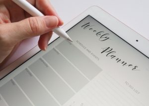 a woman creating a schedule in her weekly planner