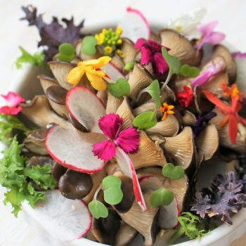 Fresh paleo-friendly raw salad with mushrooms and edible flowers