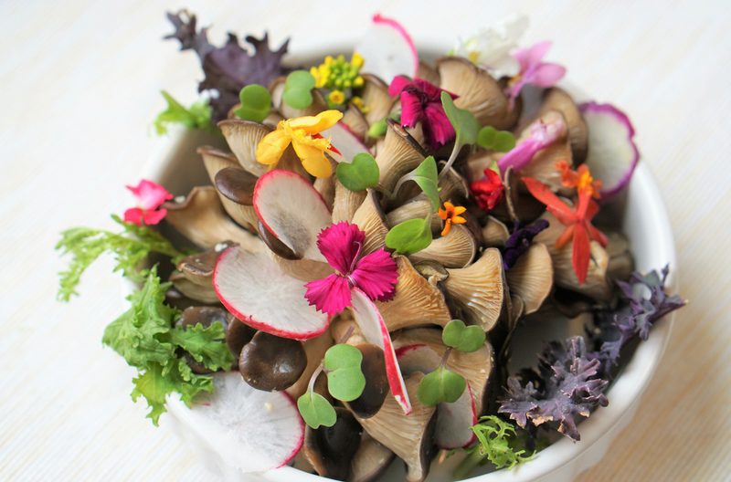 Fresh paleo-friendly raw salad with mushrooms and edible flowers