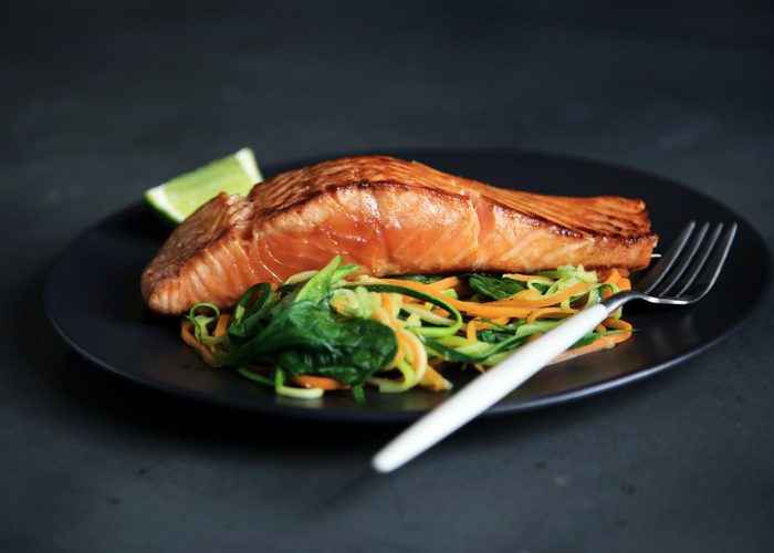 roasted salmon fillet on a bed of spiralized veggies on a black plate