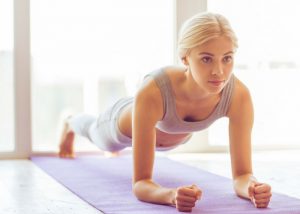 woman doing planks on a purple yoga mat