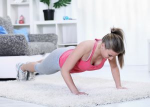 woman doing push ups in her living room on a plush white carpet