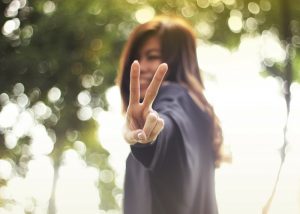 a woman smiling and making the peace sign