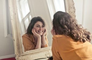 A woman smiling at herself in the mirror