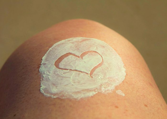 a heart drawn in lotion on a woman's knee