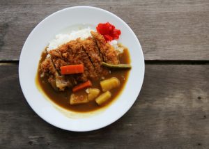a plate of japanese curry with white rice and fried pork cutlet