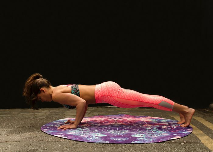 woman in yoga outfit doing push ups on a round purple mat