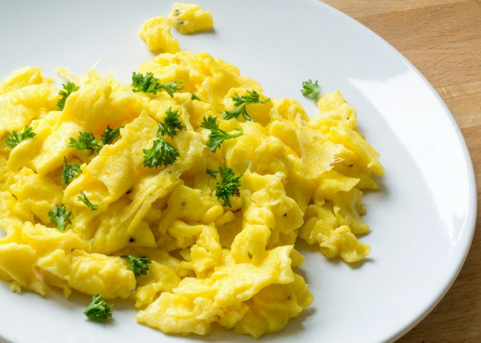 a plate of scrambled eggs topped with parsley