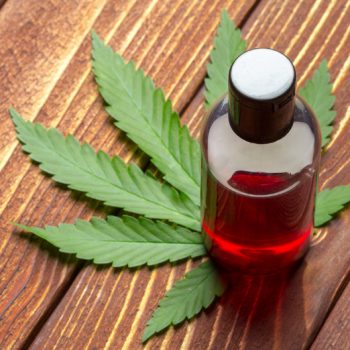 CBD cannabis oil in a brown vial on top of a cannabis leaf