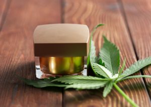 cbd cannabis oil in a square container with cannabis leaves beside it