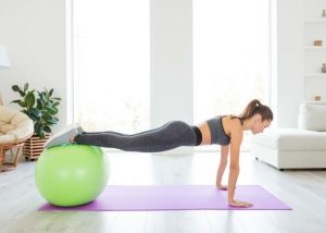 woman with an exercise ball in plank position doing chest exercises at home