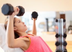 woman doing dumbbell chest exercises at the gym