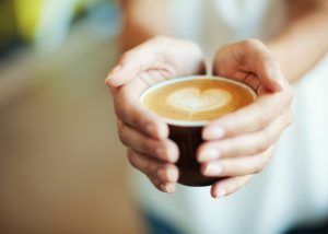 closeup of a woman's hands holding a latte