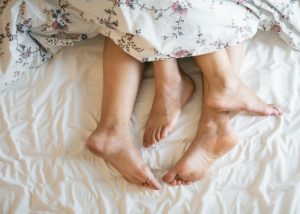 closeup of a couple's feet sticking out from the covers in bed