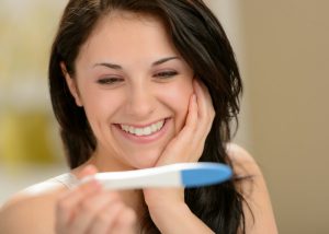 woman holding pregnancy test and smiling