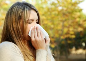 woman with allergies blowing her nose