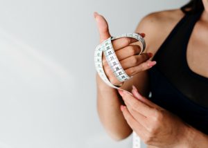 fit woman with a measuring tape wrapped around her hand