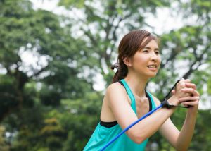 woman in a teal tank top doing resistance band training outdoors