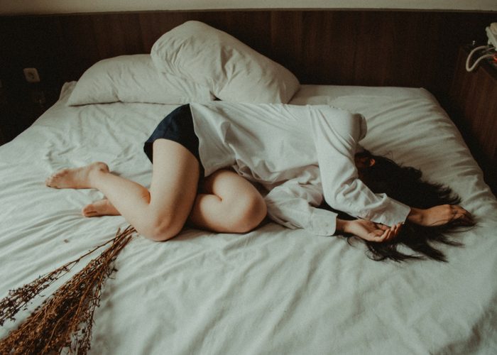 depressed woman curled up in bed