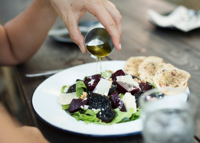 woman pouring oil over her green salad