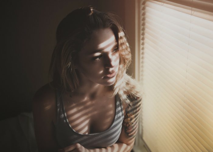 woman looking out at the closed shutters of her window