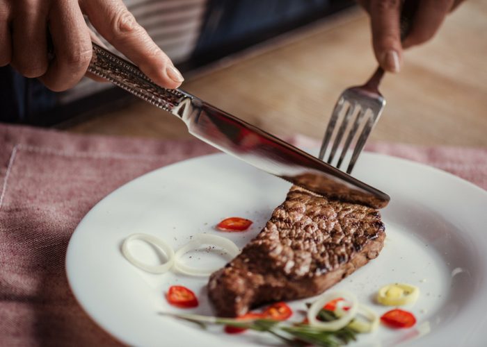 woman cutting into a piece of steak