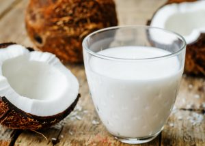 a glass of coconut milk and fresh coconut around it