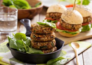 stacked vegan lentil burger patties with vegan burgers in the background