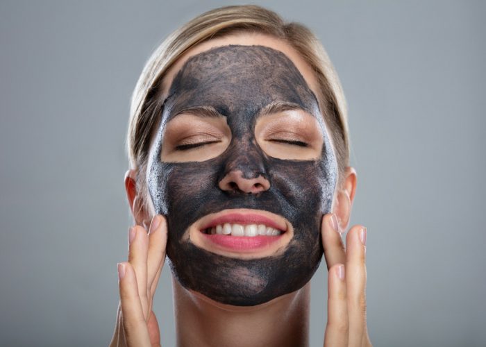 smiling woman using an activated charcoal cleanser in her best skin care routine