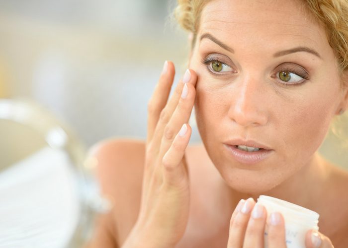 woman applying skin care products to her face