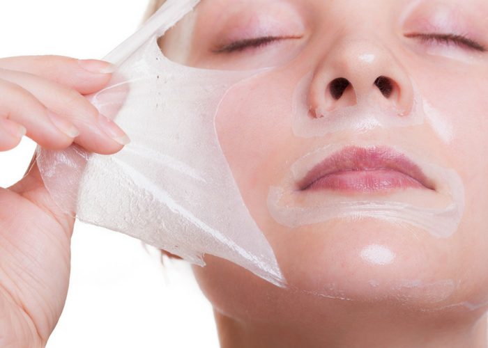 woman peeling off a hydrating face mask during her skin care routine