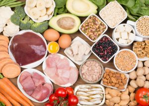 table filled with biotin-rich foods such as avocado, eggs, nuts, liver, broccoli