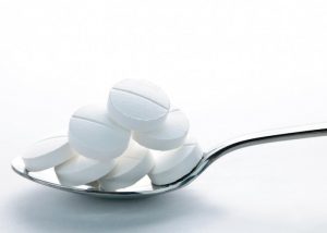 white calcium supplement tablets on a silver spoon