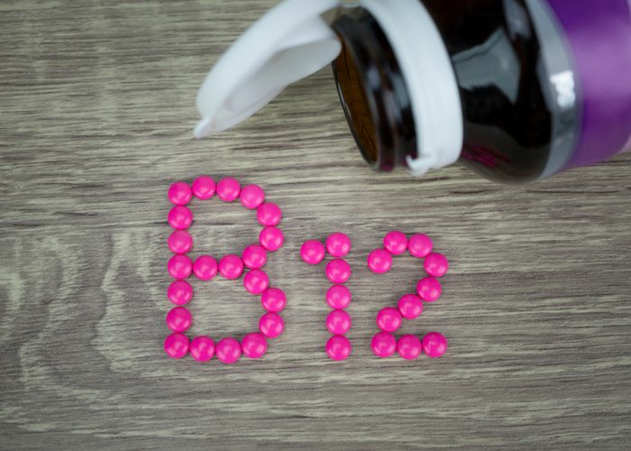 B12 spelt out in pink pills next to an open supplement bottle